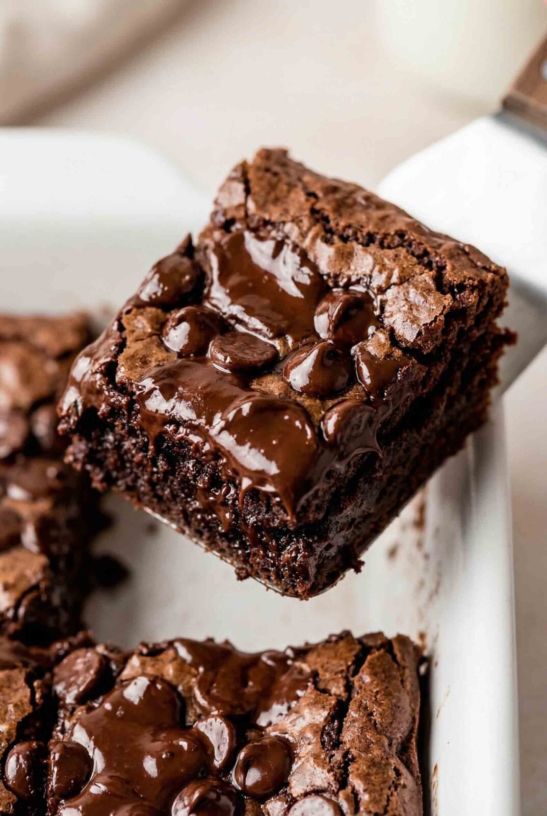 Extreme close-up of a gooey chocolate dump cake with melted chocolate chips and a slice lifted from the baking dish