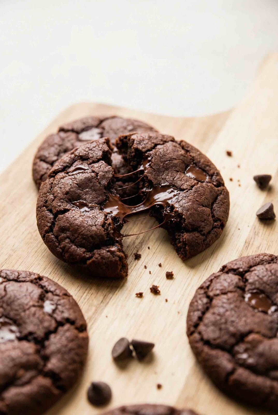 Overhead macro of double chocolate chip cookies with one cookie broken open showing melted chocolate