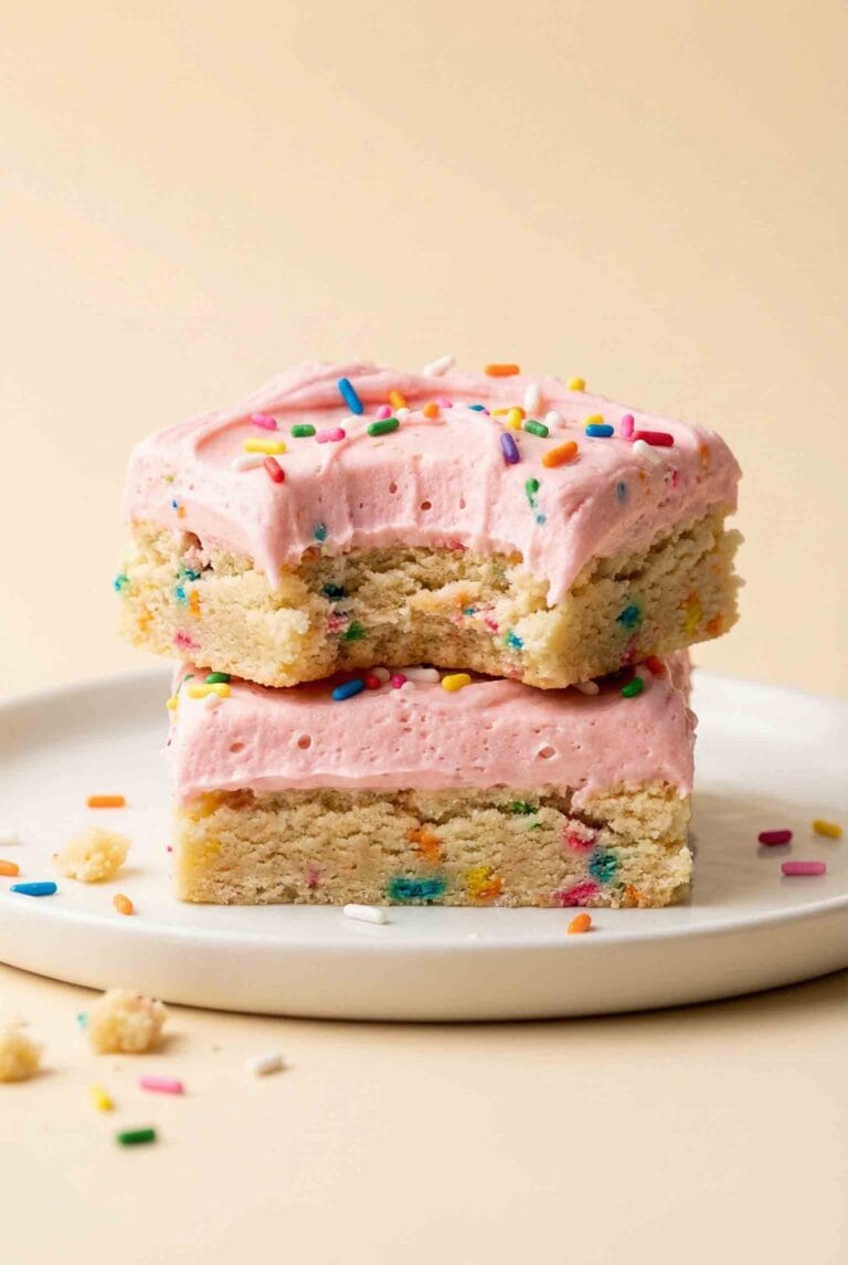 Vertical hero image of frosted sugar cookie bars stacked on a white ceramic plate with pink frosting and colorful sprinkles on a warm cream background.