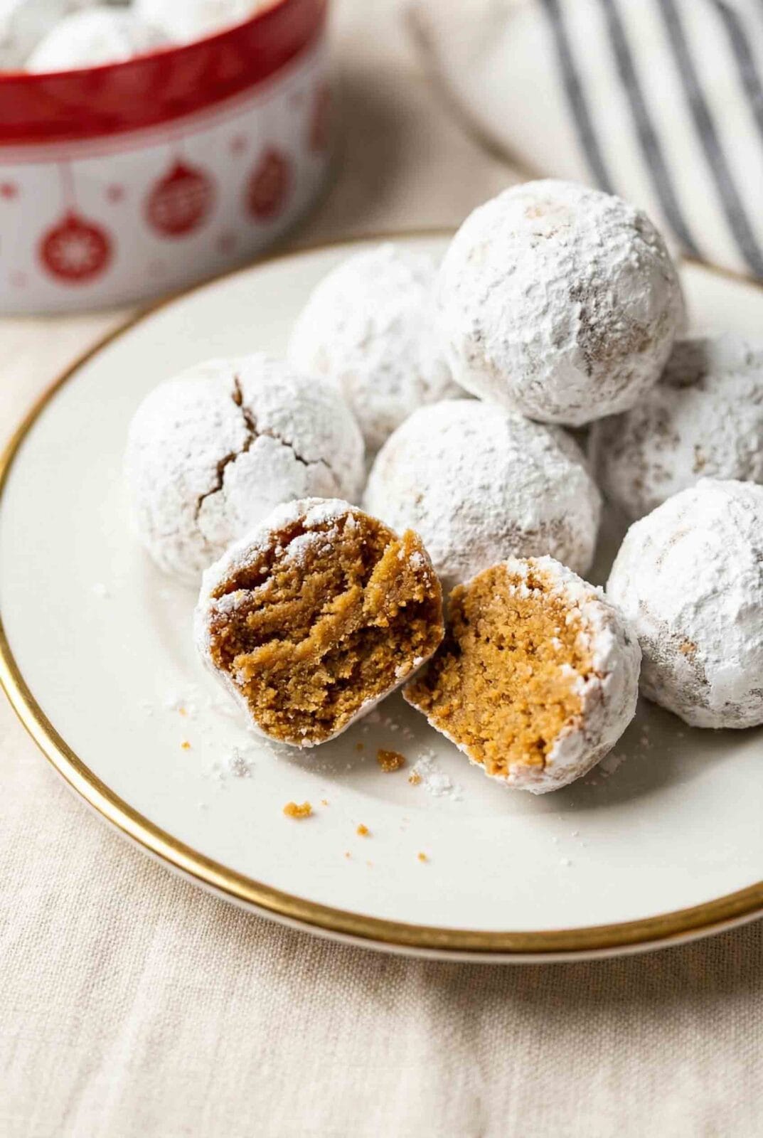 No-bake gingersnap balls with powdered sugar coating on white plate, one broken to show crushed cookie interior texture