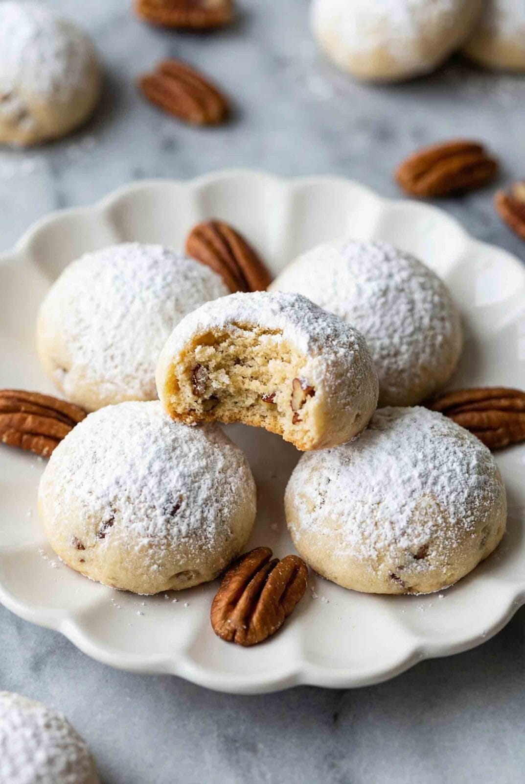 Macro view of a bitten snowball cookie revealing detailed interior crumb on a white plate with almonds